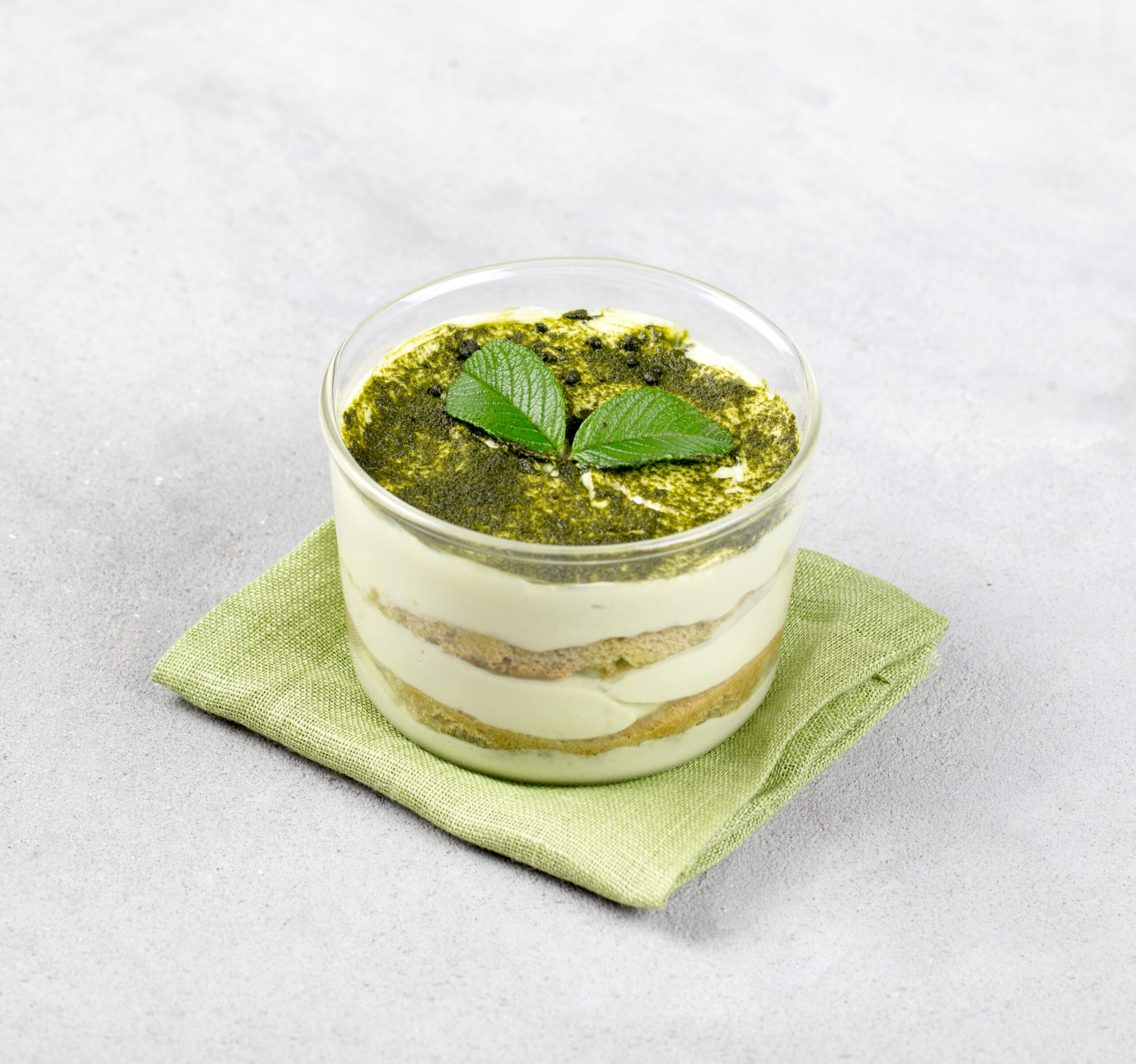 italian dessert tiramisu with green matcha tea in a glass Cup on